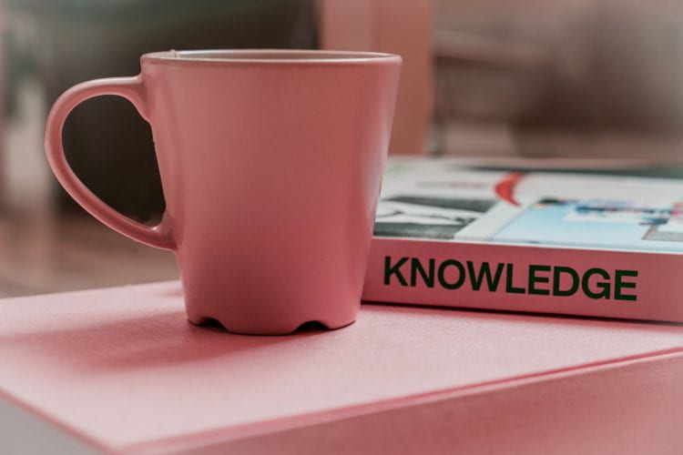 Cup next to a book called 'Knowledge'